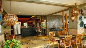 Un vaste espace dédié à la salle à manger, avec une grande table et des chaises, une cuisine en arrière-plan et des œuvres d’art décoratives sur les murs.