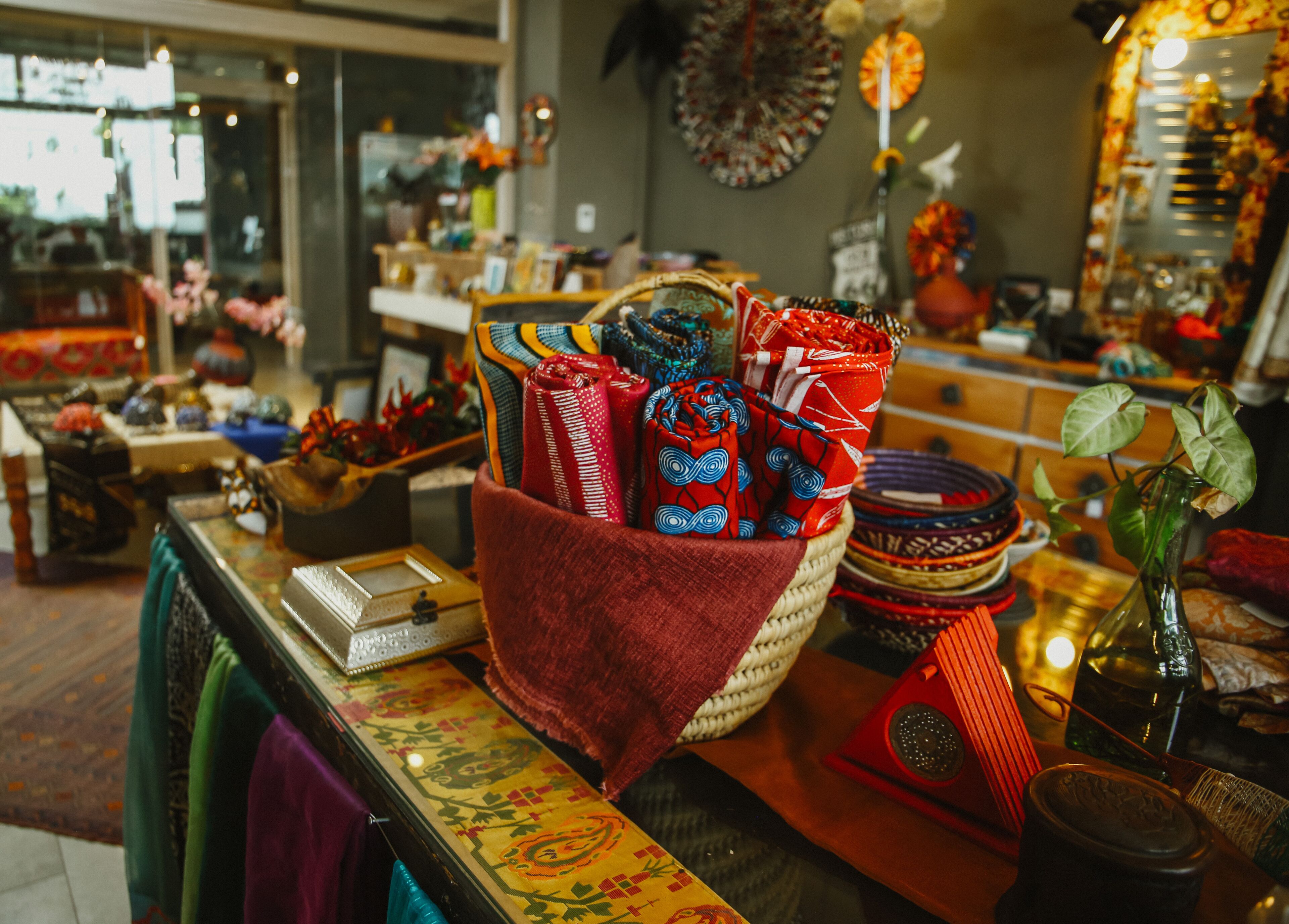 Une exposition de textiles colorés et d’objets décoratifs disposés sur une table.