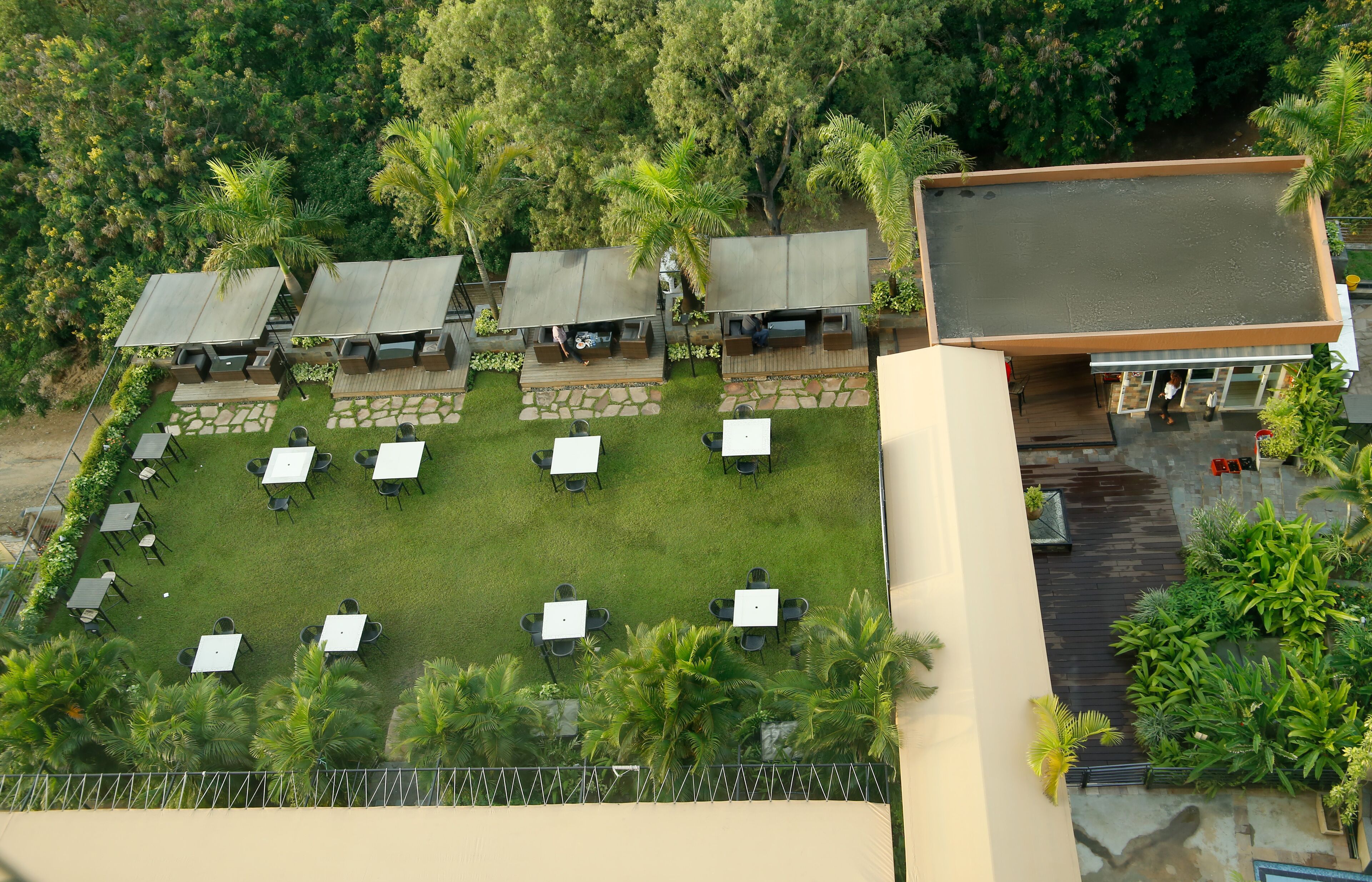 Vista aérea de un complejo turístico con zonas de estar al aire libre, piscina y abundante vegetación.