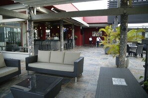 Un espace extérieur aménagé avec un bar, des canapés confortables et un sol carrelé en pierre.