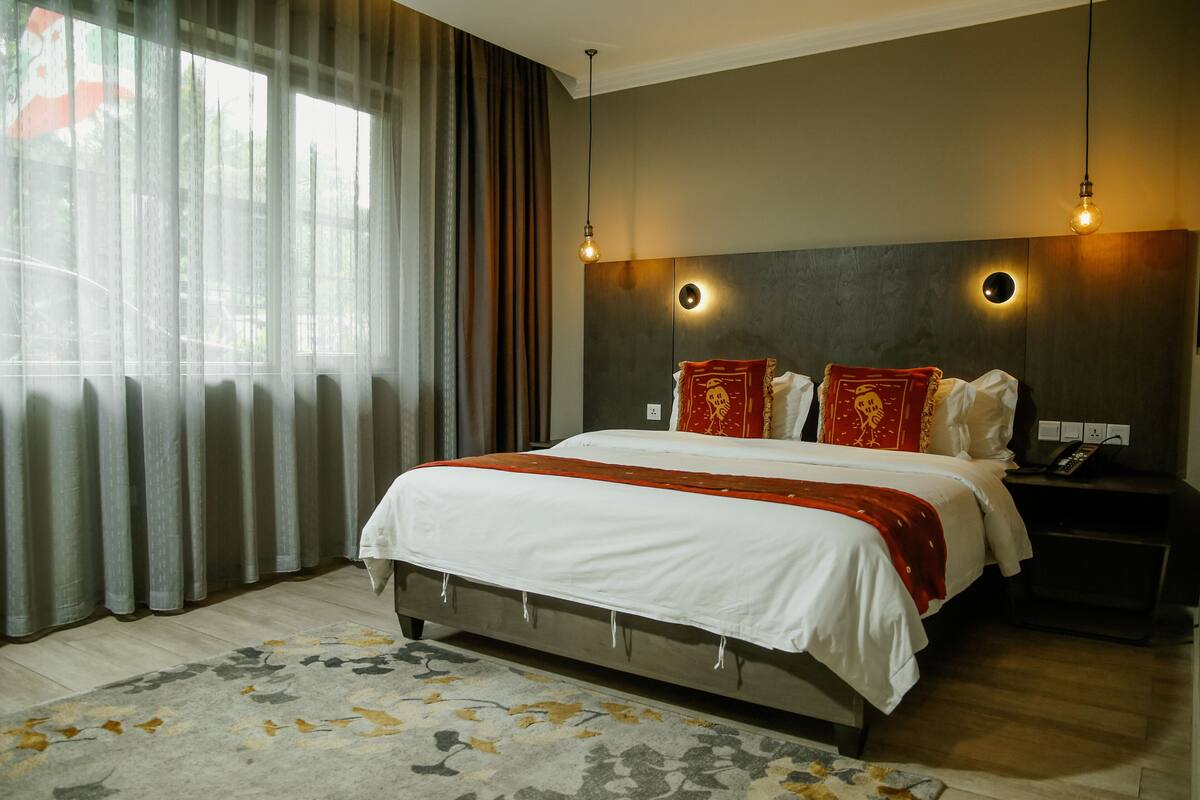 Una habitación de hotel moderna con una cama grande, una mesita de noche con un teléfono y una lámpara fijada a la pared.