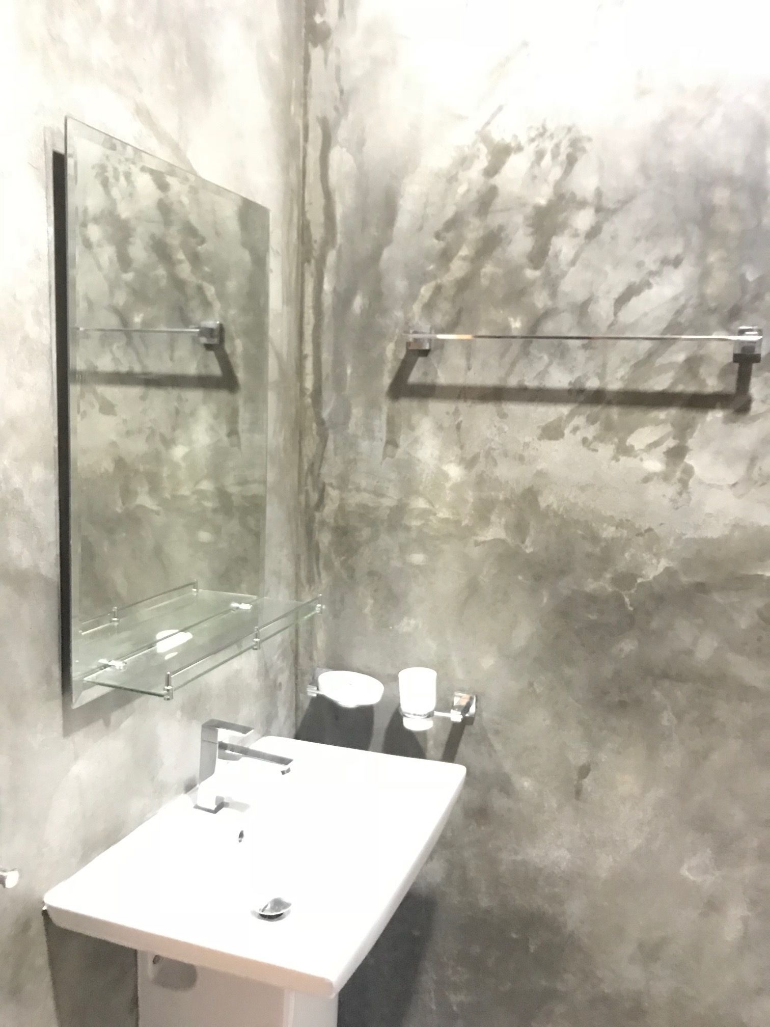 A bathroom with a white sink, a mirror, and a towel rack.