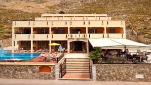 Een hotel met een zwembad, buiten zitplaatsen en een bergachtige achtergrond.