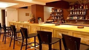 Een bar met houten toonbanken, verschillende flessenkasten vol drank en een stap sinaasappels aan de rechterkant.