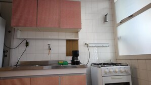 Een keuken met witte betegelde wanden, een gasfornuis, een koffiezetapparaat en keukenkastjes met een geruit patroon.