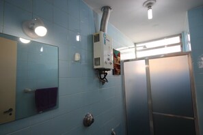 Un baño con azulejos azules, un perchero, una unidad de ventilación y una zona de ducha.