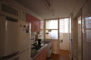 Una cocina compacta con refrigerador, estufa y pileta.