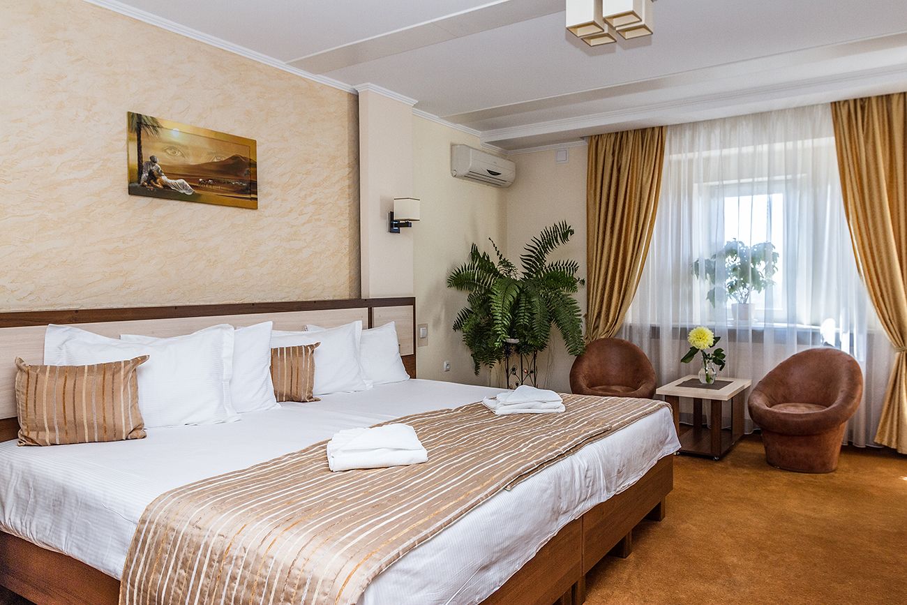 Habitació d'hotel amb un llit gran, una taula petita amb un ram, dues cadires i un quadre a la paret.