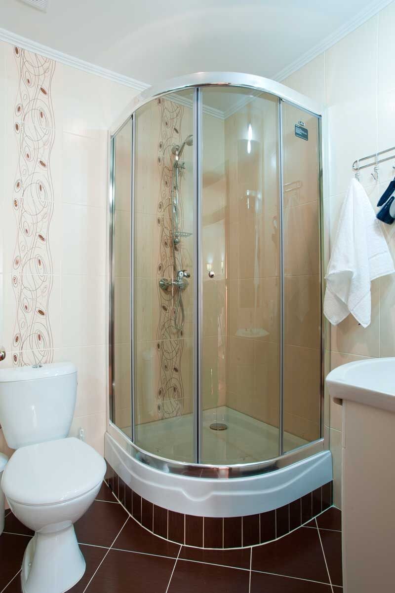 A bathroom with a glass-enclosed shower, a toilet, and a sink.