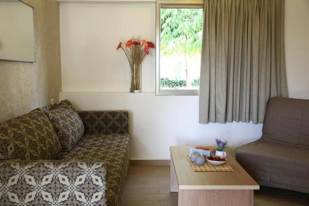 Un salón con sofás estampados, una mesita con un cuenco y un jarrón, y una ventana con cortinas.