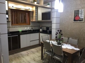 A compact kitchen with a dining area, featuring a microwave, stove, and cabinets.