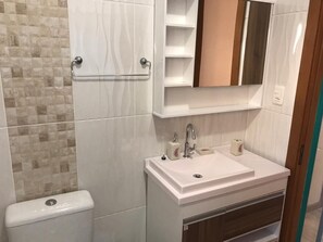 A bathroom with a toilet, a sink, and a mirror.