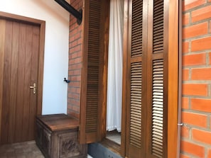 A wooden door, a brick wall, and wooden shutters.