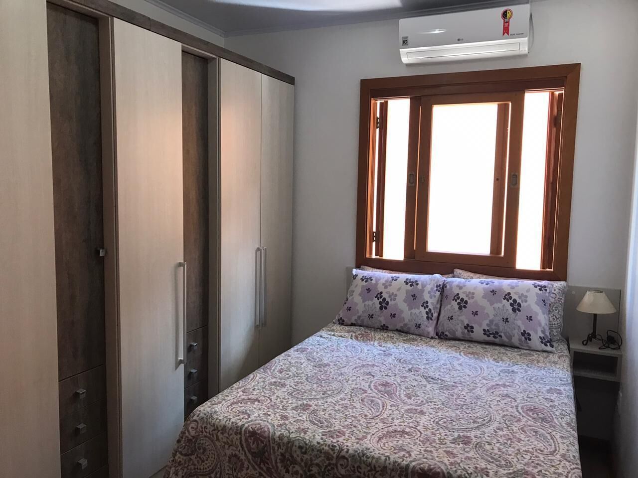 A bedroom with a bed, a wardrobe, a nightstand, and a window with curtains.