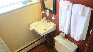 A bathroom with a white sink, mirror, and toilet. There are white towels hanging on a rack. - Cianci's Motel and Suites (Greenville)