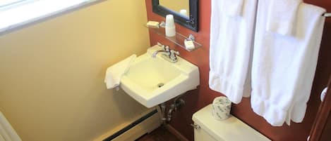 A bathroom with a white sink, mirror, and toilet. There are white towels hanging on a rack.