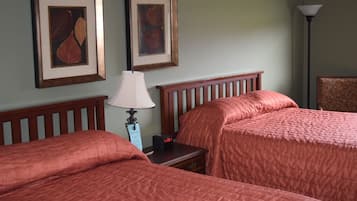 Una habitación de hotel con dos camas, una mesita de noche con lámpara y cuadros en la pared.