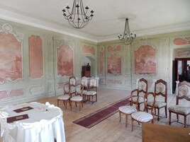 Una habitación con paredes decorativas, candelabros y una mesa dispuesta para una reunión.