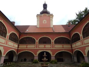 Un edificio con una cúpula central, ventanas en arco y un patio con una fuente.