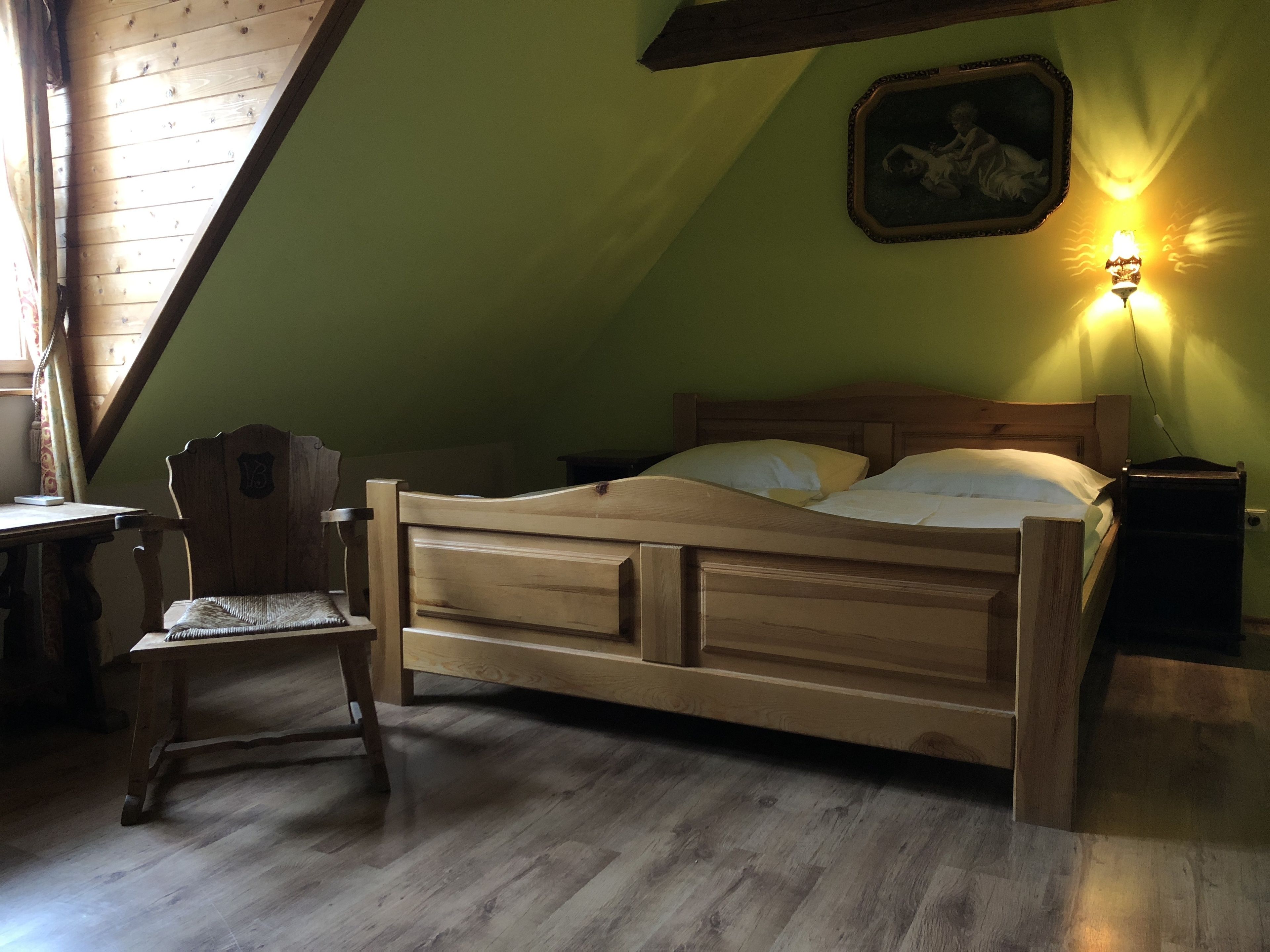 Ein Bett aus Holz in einem Zimmer mit schräg versiegelter Decke und grüner Wand.