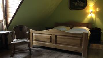 Ein Bett aus Holz in einem Zimmer mit schräg versiegelter Decke und grüner Wand.