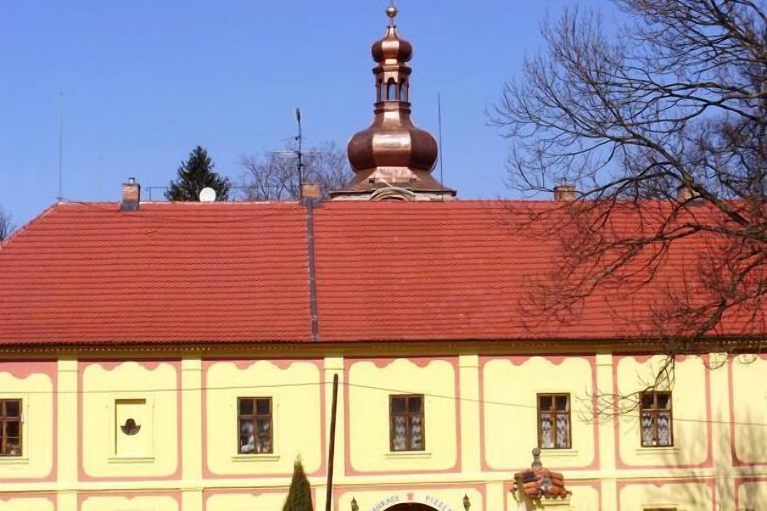 Un bâtiment doté d’un toit rouge et d’une façade jaune, avec un dôme imposant et plusieurs fenêtres.