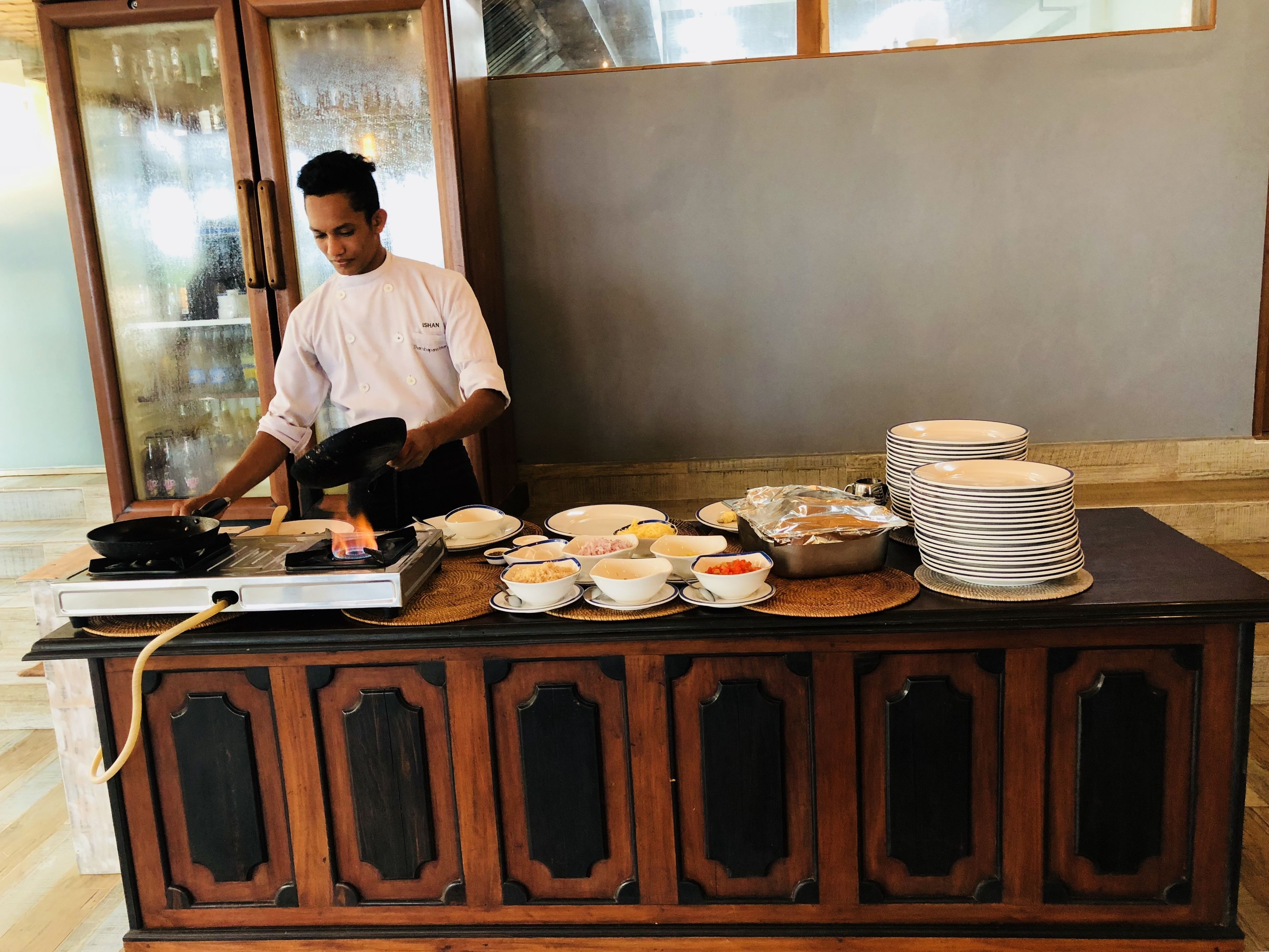 A chef cooking on a stove in a kitchen area with various dishes and plates on a counter.
