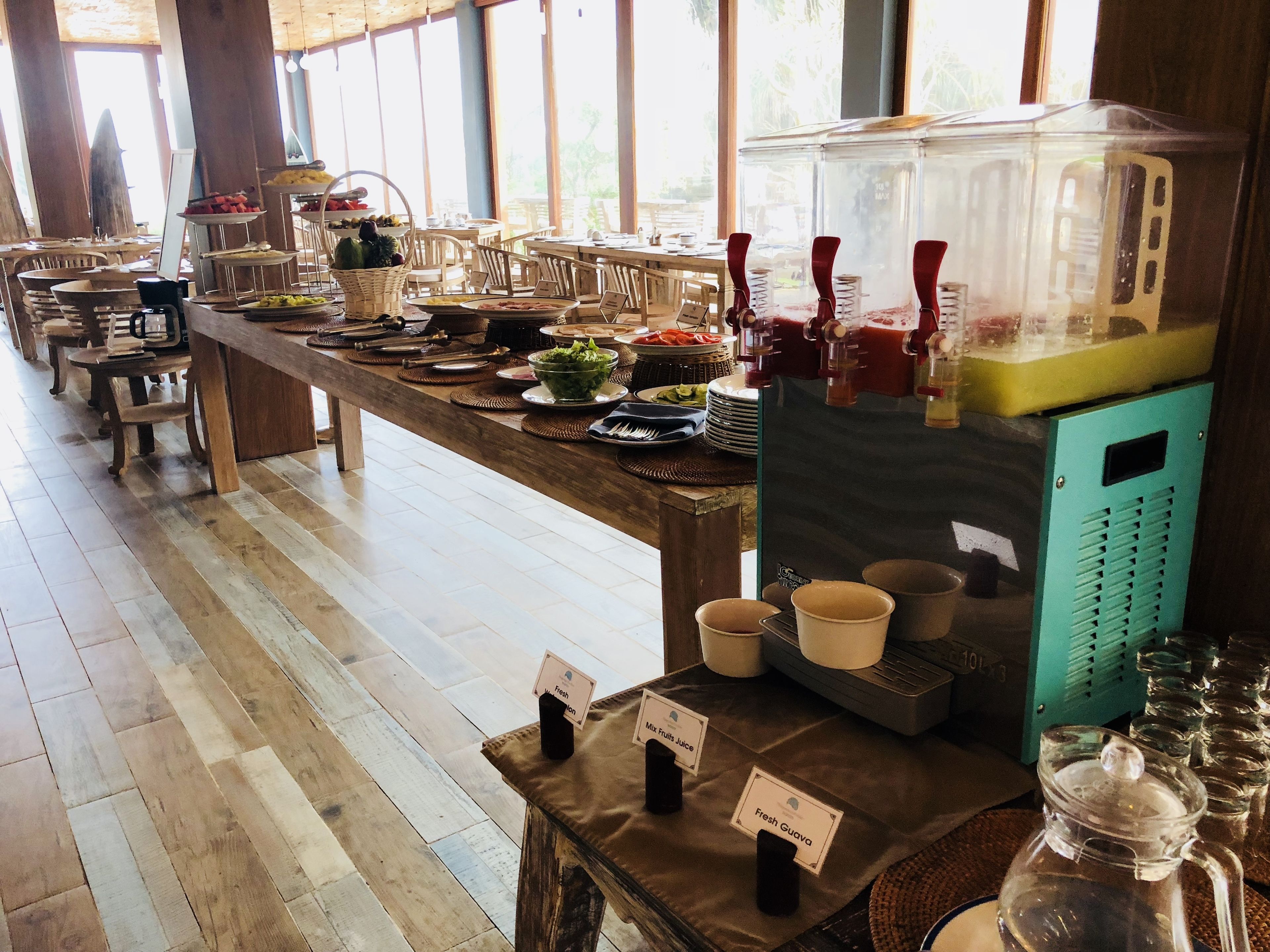 A buffet setup with various food items and a juice dispenser.