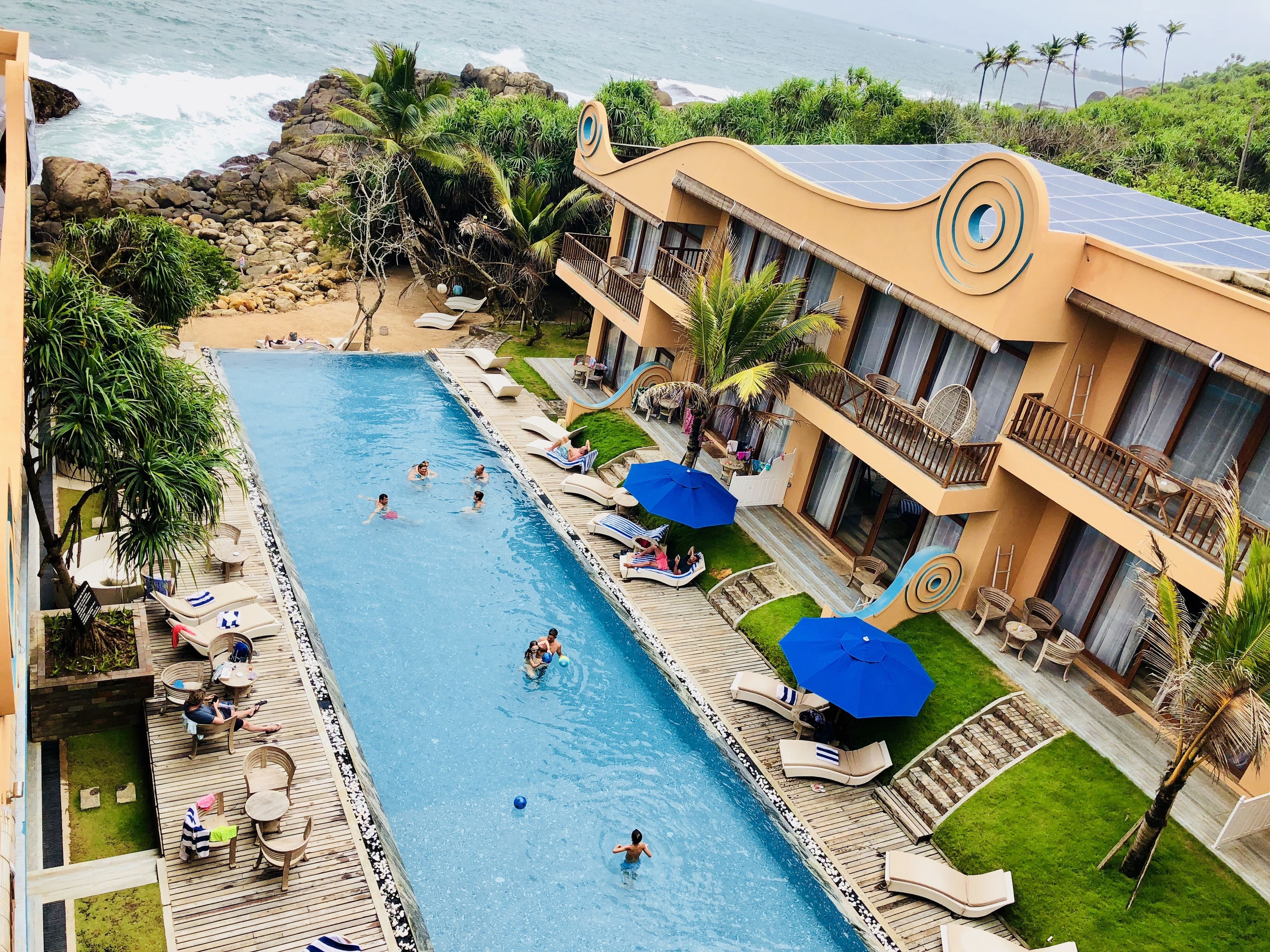 A resort with a swimming pool, lounge chairs, and a view of the ocean.