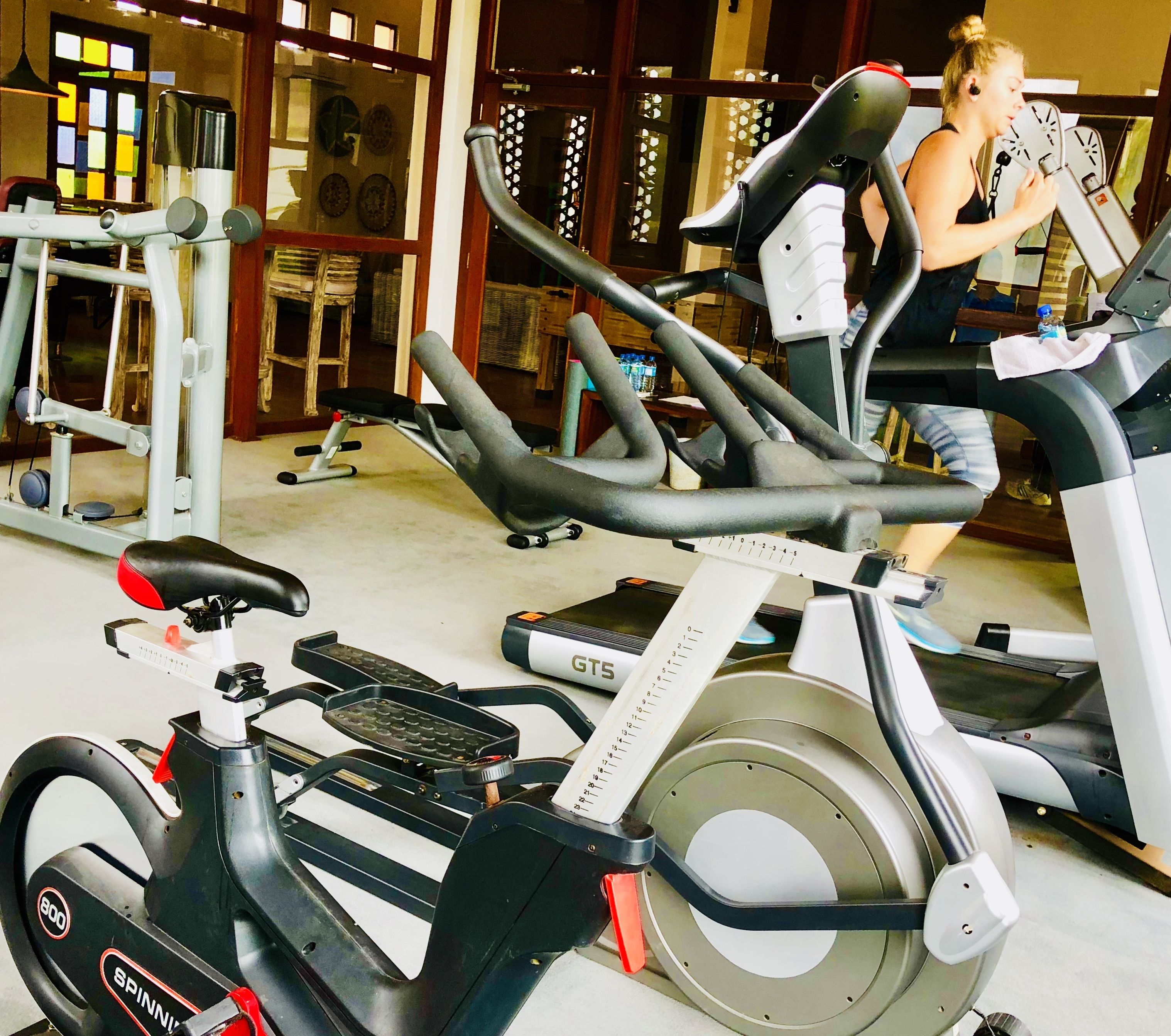 Un gimnasio con bicicletas estáticas, máquinas de pesas y una cinta de correr.