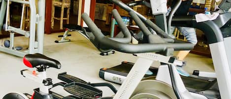 Un gimnasio con bicicletas estáticas, máquinas de pesas y una cinta de correr.