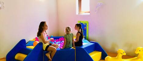 Zona de juegos con piscina de pelotas, tobogán y juguete con forma de pato.