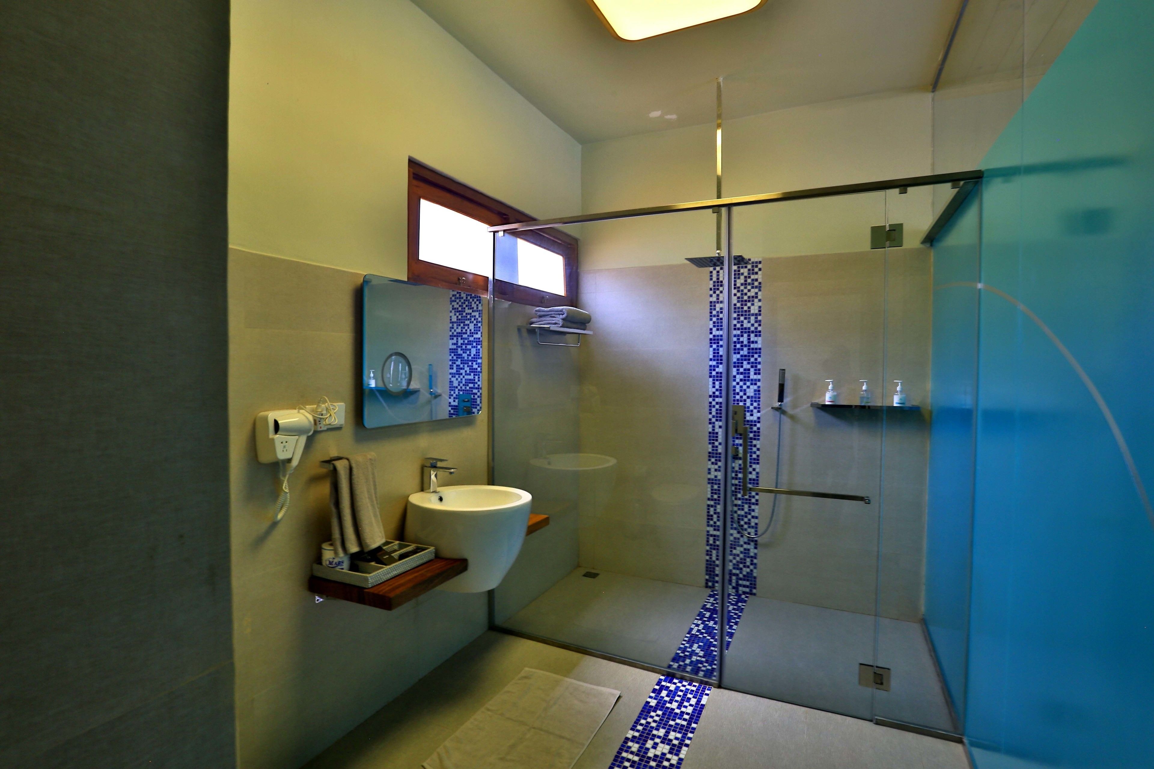Un baño moderno con cabina de ducha de vidrio, un lavamanos y un espejo.