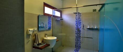 Un baño moderno con cabina de ducha de vidrio, un lavamanos y un espejo.