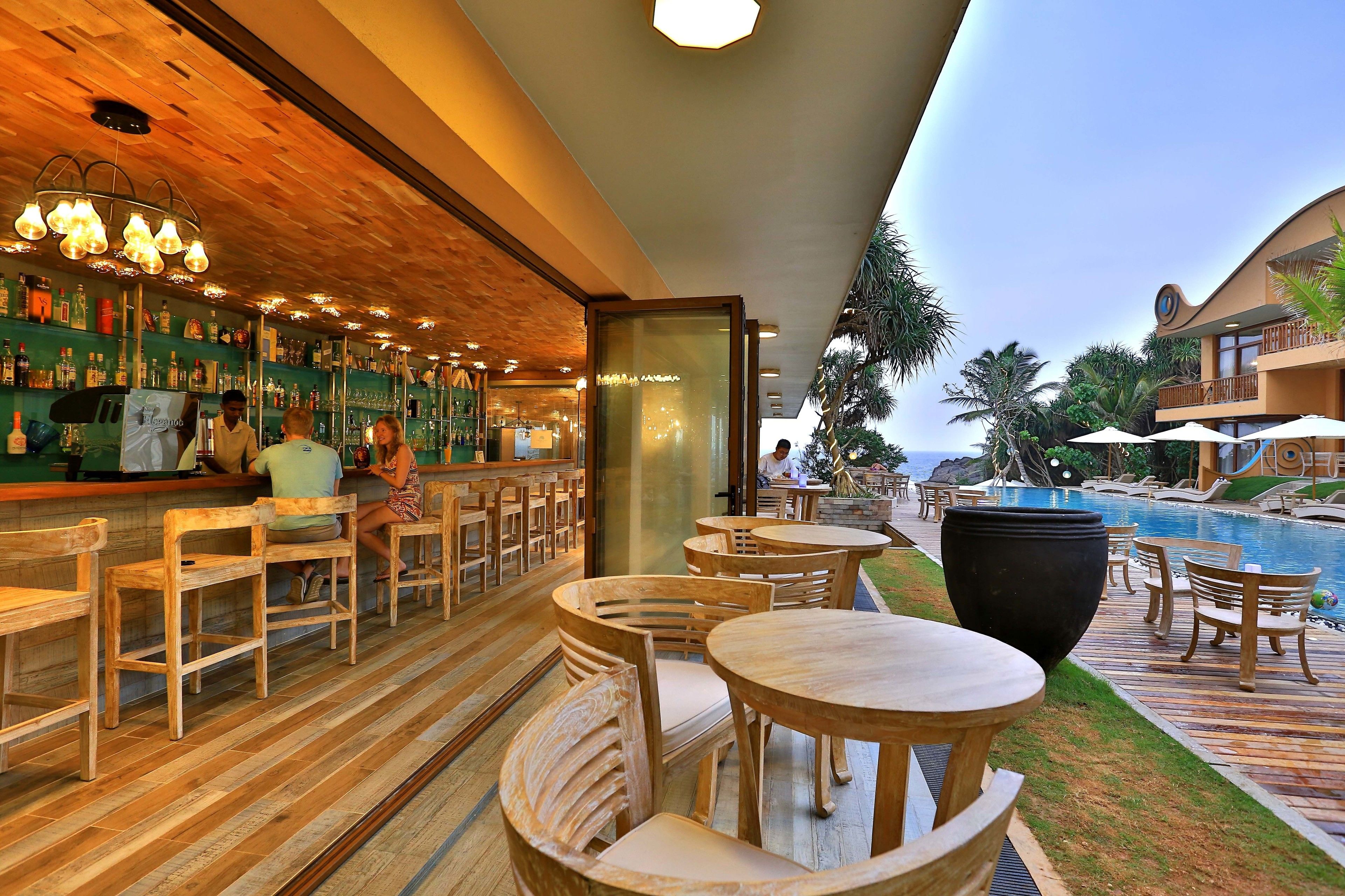 A bar area with wooden furniture and a poolside seating area with tables and chairs.