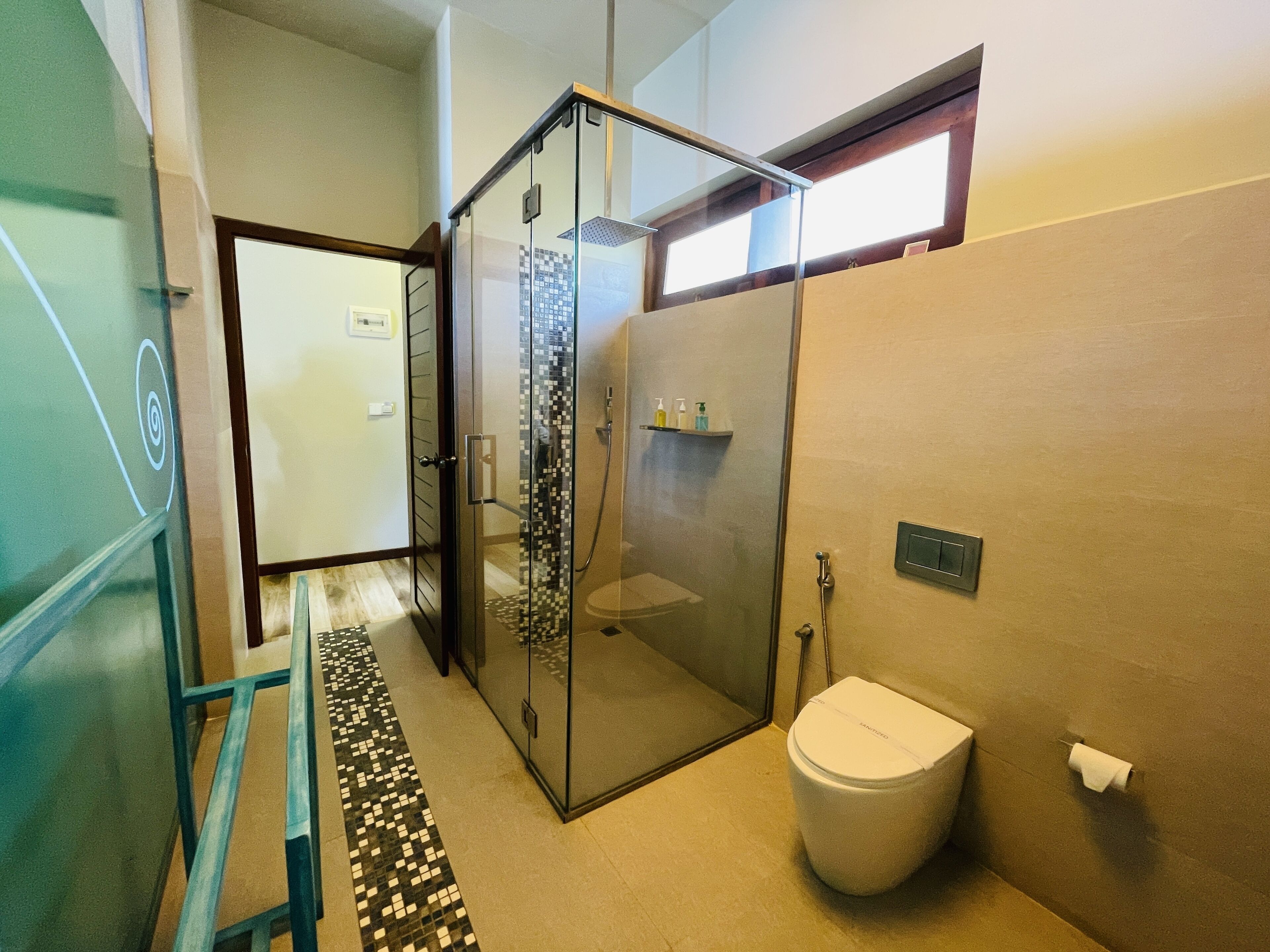 Une salle de bain moderne avec une douche à parois de verre, des toilettes et une petite étagère contenant des articles de toilette.
