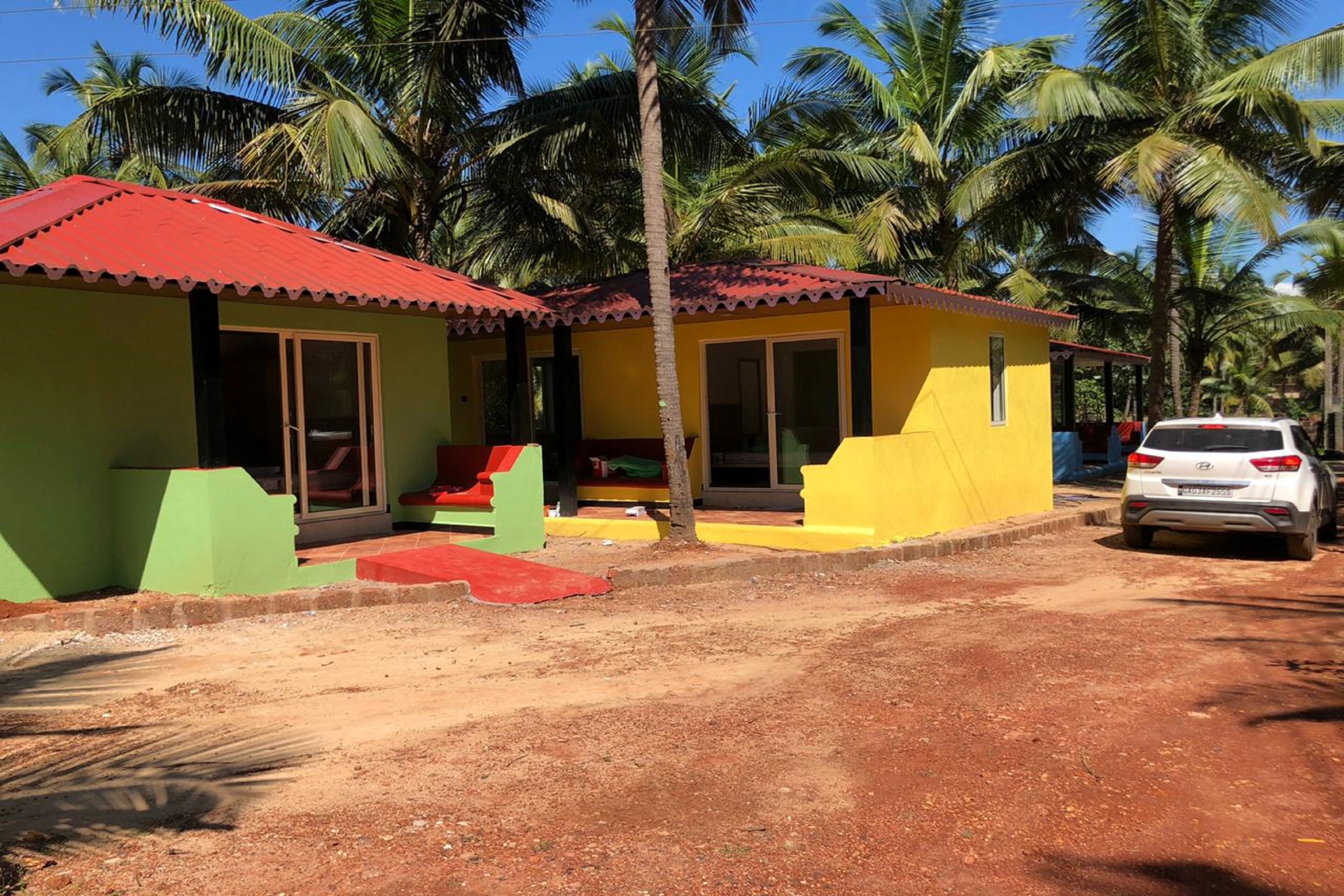 Un edificio de dos pisos con techo rojo y paredes amarillas, que cuenta con ventanas grandes y un porche cubierto.