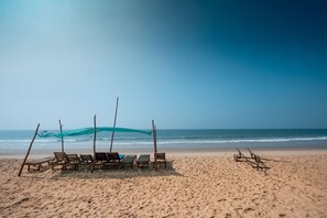 A beach with wooden chairs and a canopy, a sandy beach, and the ocean in the background. - Kay's By The Sea (Vengurla)