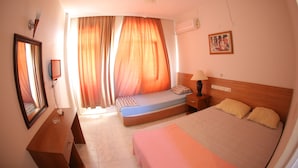 A bedroom with a bed, bedside table, lamp, and a mirror. - Mavi Cennet Camping Pansiyon (Manavgat)