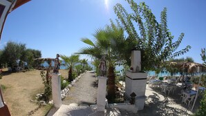 A pathway leading to outdoor seating with a view of the sea. - Mavi Cennet Camping Pansiyon (Manavgat)