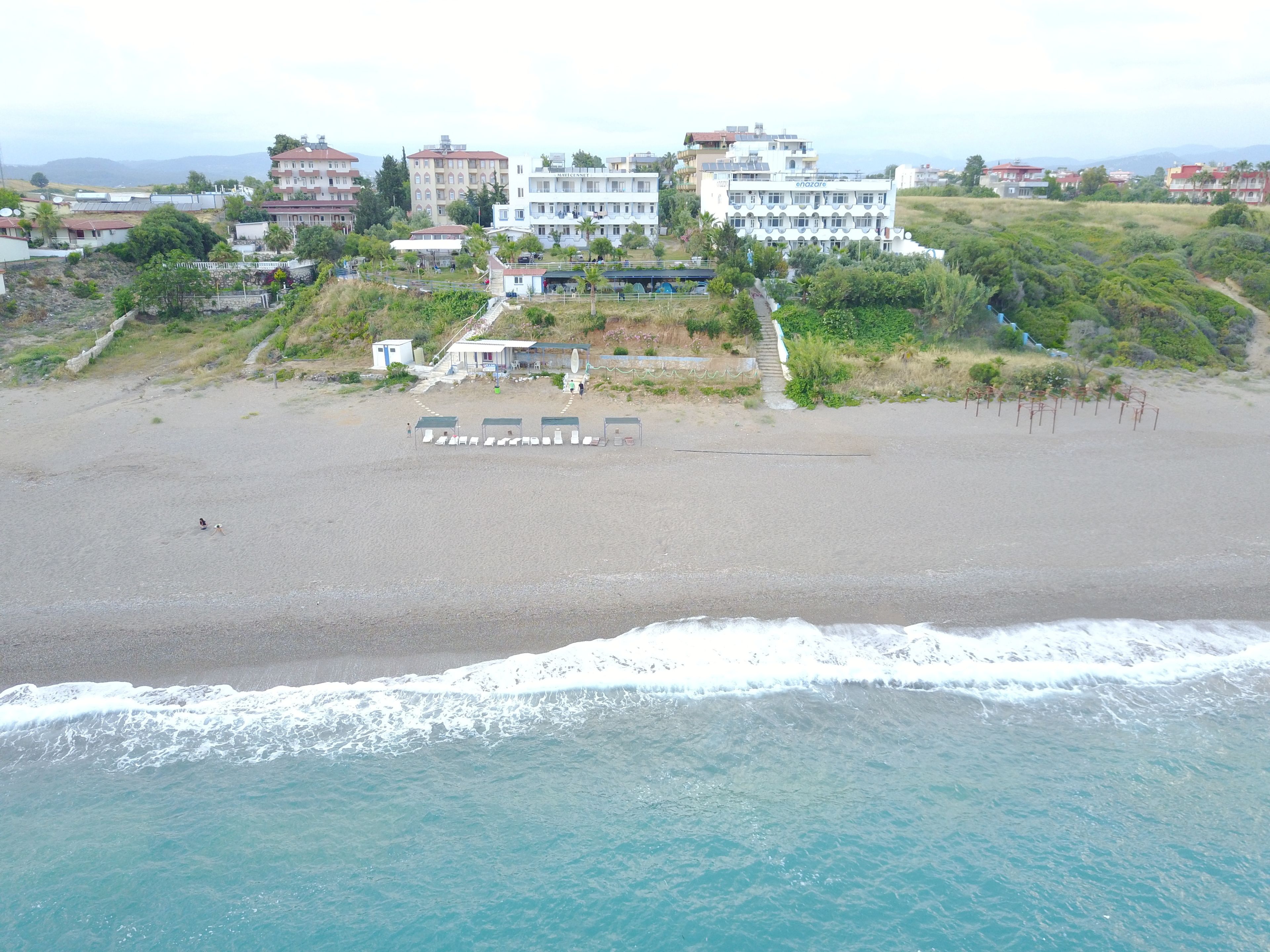 A beach with a row of beach huts and a building with a sign that reads "enazare".