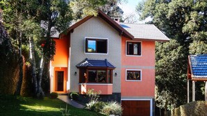 Une maison à deux étages avec une façade en briques, une porte d’entrée en bois et un petit porche.