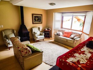 A living room with a sofa, armchair, and a fireplace. - Bella Casa Condominio Centro Gramado (Gramado)