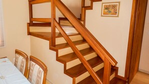 Un escalier en bois au motif géométrique, une table à manger avec des chaises et un tableau encadré au mur.
