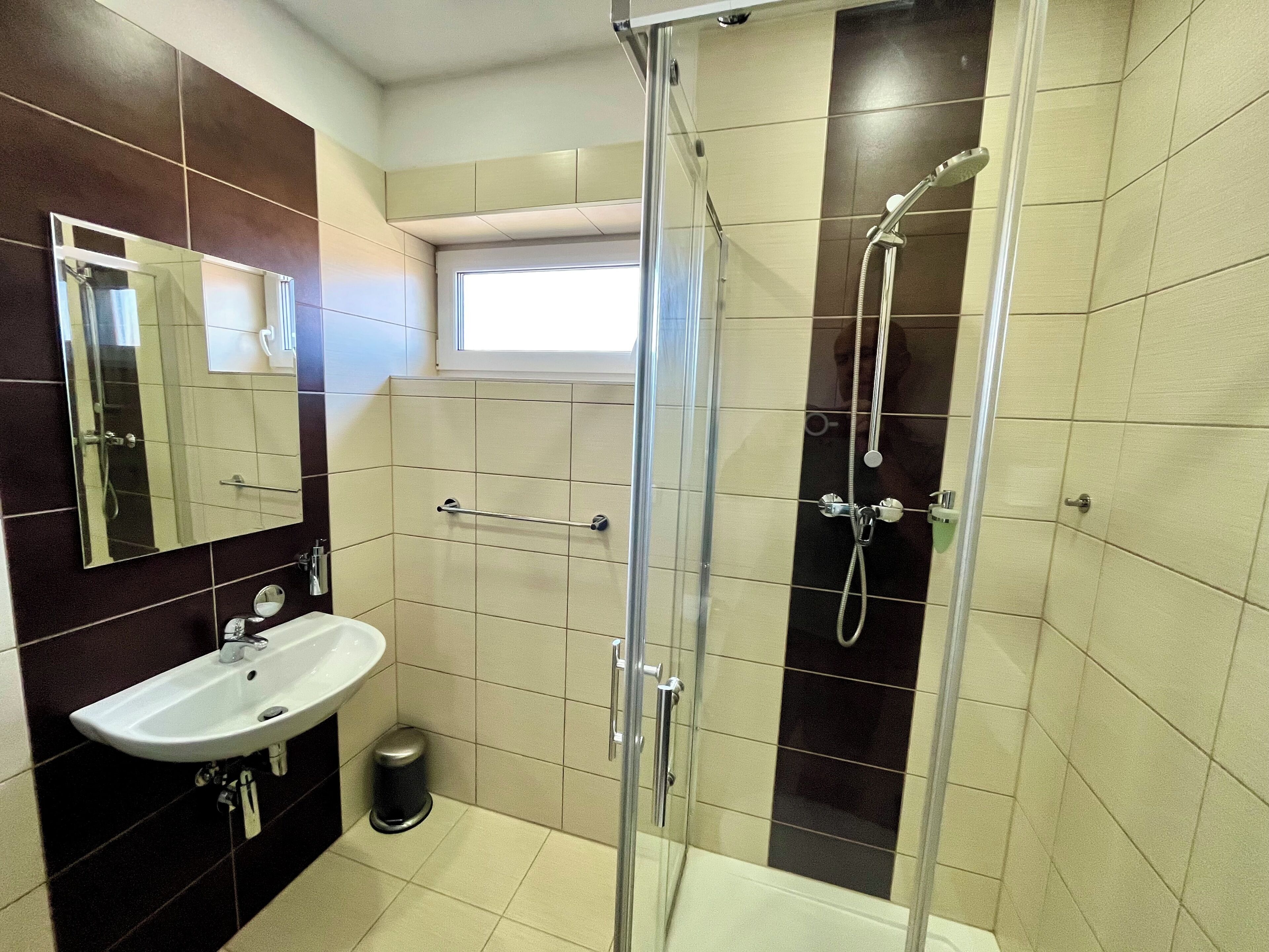 Ein modernes Badezimmer mit einer Glaskabine zur Dusche, einem Waschbecken und einem Spiegel.