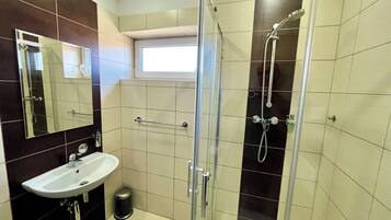 Ein modernes Badezimmer mit einer Glaskabine zur Dusche, einem Waschbecken und einem Spiegel.