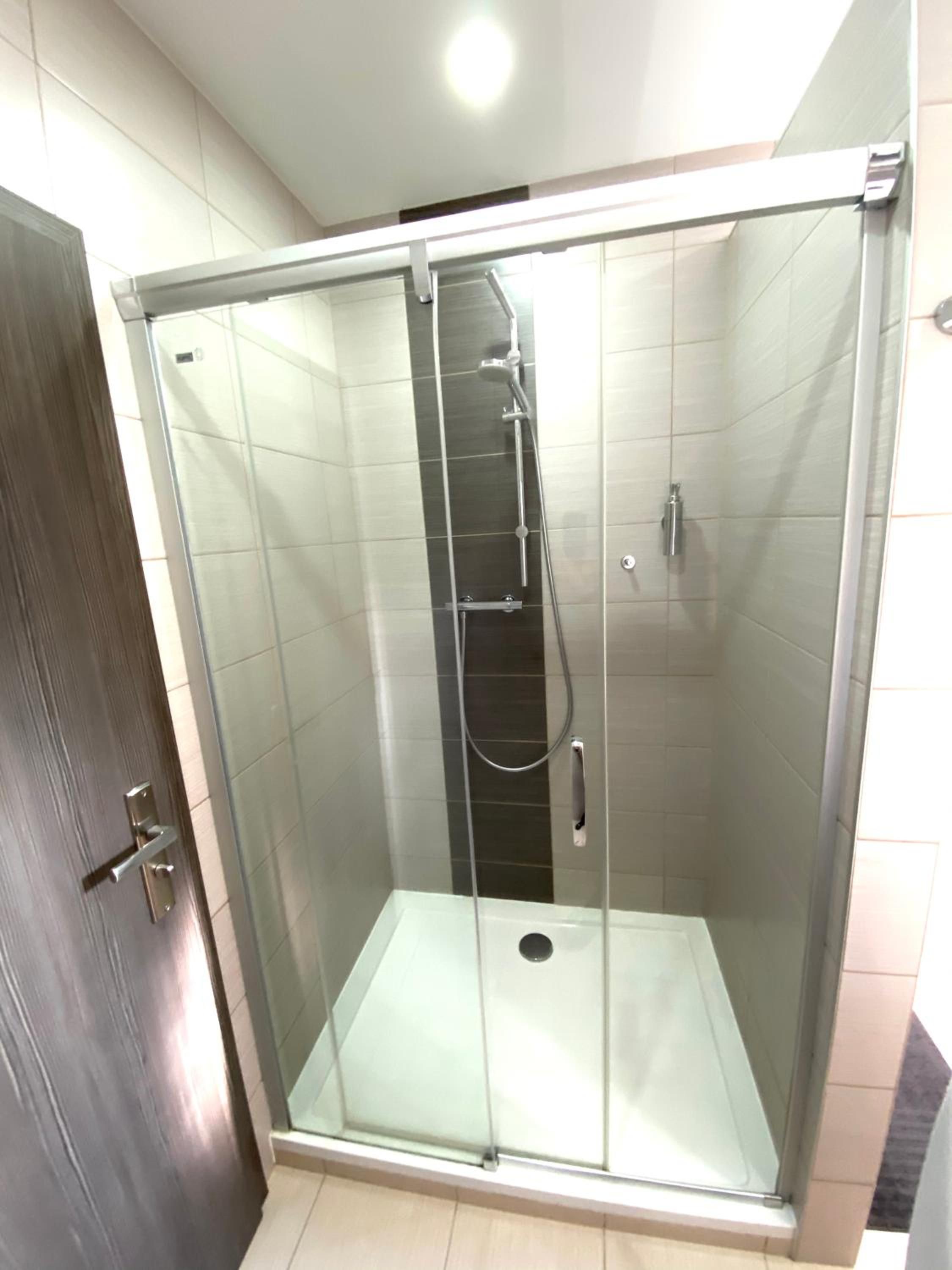 Une cabine de douche fermée par des parois en verre, équipée d’un pommeau de douche et d’un panneau de commande.