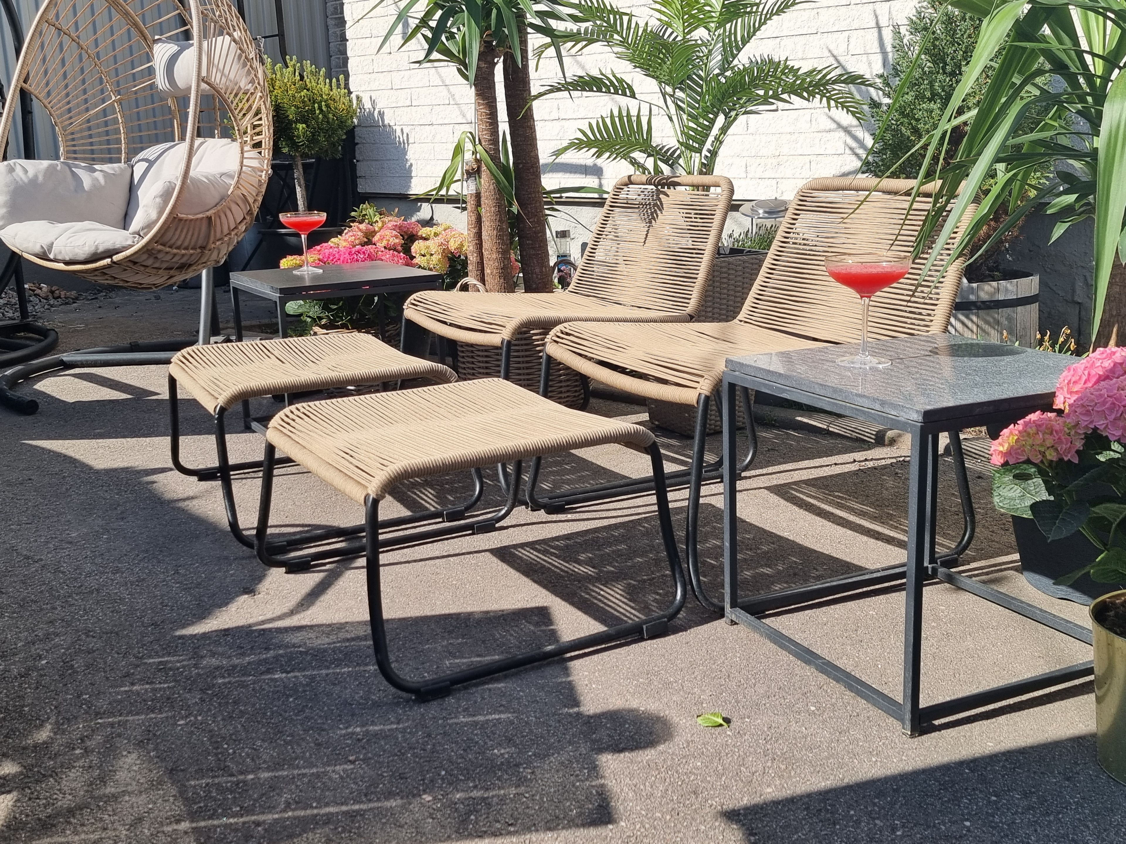 Outdoor seating with wicker chairs and tables, a hanging chair, and potted plants.
