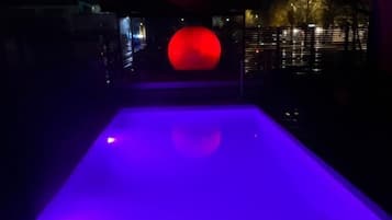 Una piscina al aire libre, sombrillas, sillones reclinables de piscina