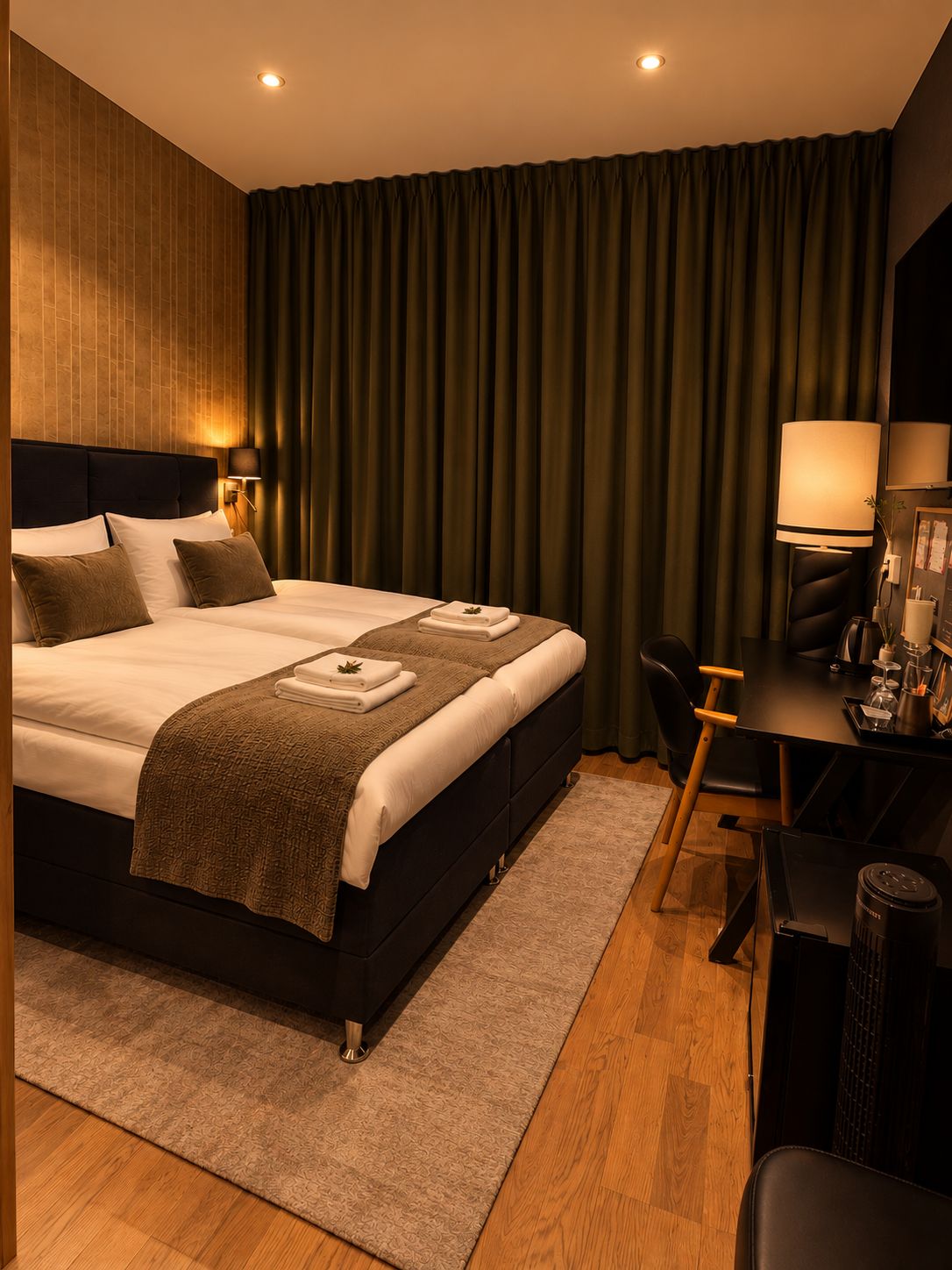 Quarto de hotel moderno com uma cama grande, uma escrivaninha com cadeira e uma luminária de mesa.
